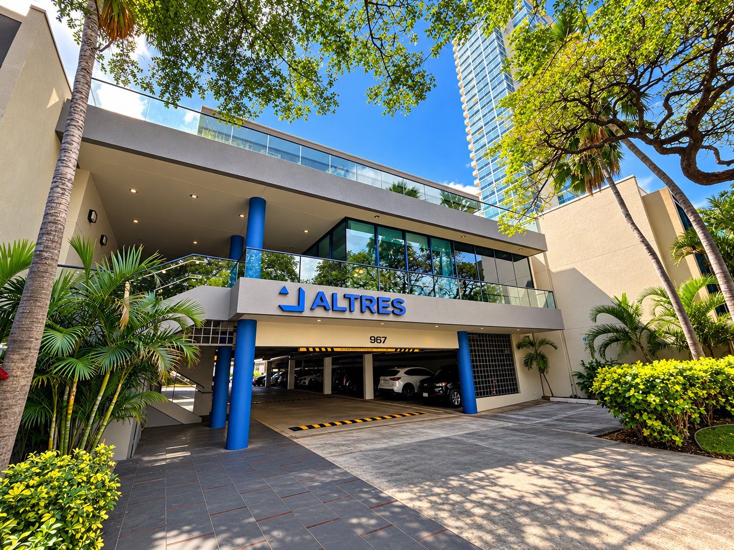 The ALTRES building, a cream low-rise with blue columns and a glass-fronted upper floor, seen from the street