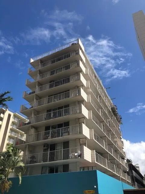 Residential high-rise in cream with white balcony rails against a blue sky