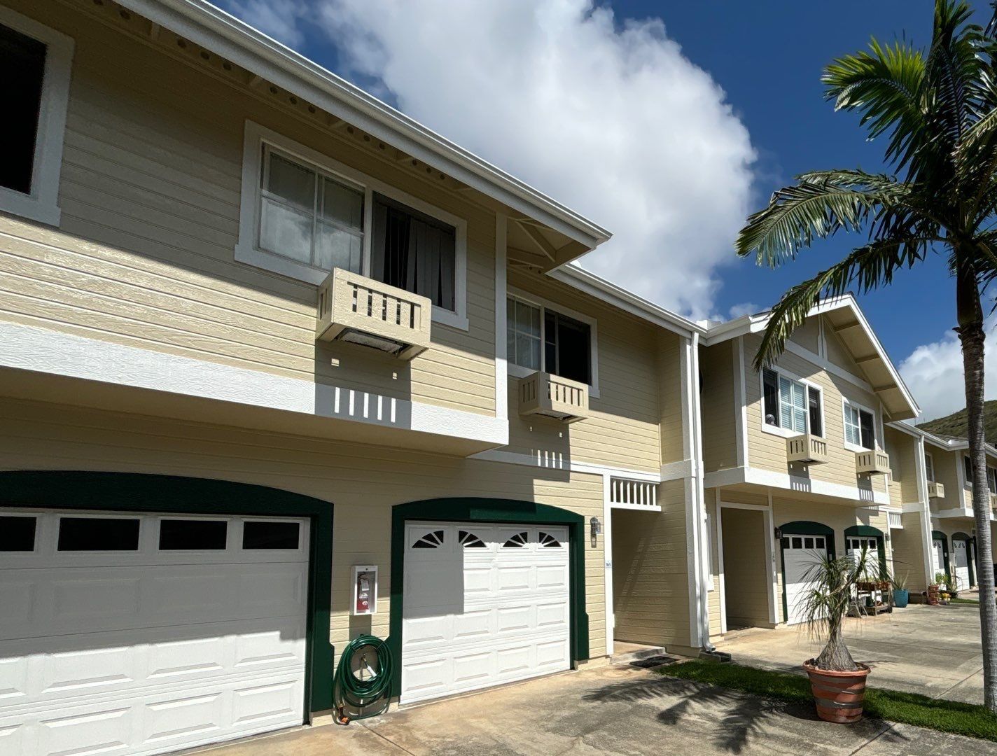 Two-story townhomes at Lalea in Hawaiʻi Kai in cream siding with white trim and green garage-door surrounds