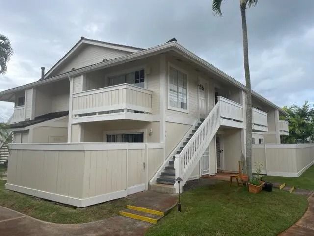 Cream two-story townhome building with white stair rails and cream fencing
