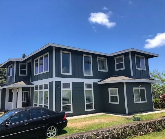 The same two-story home painted dark blue-gray with white trim and window frames