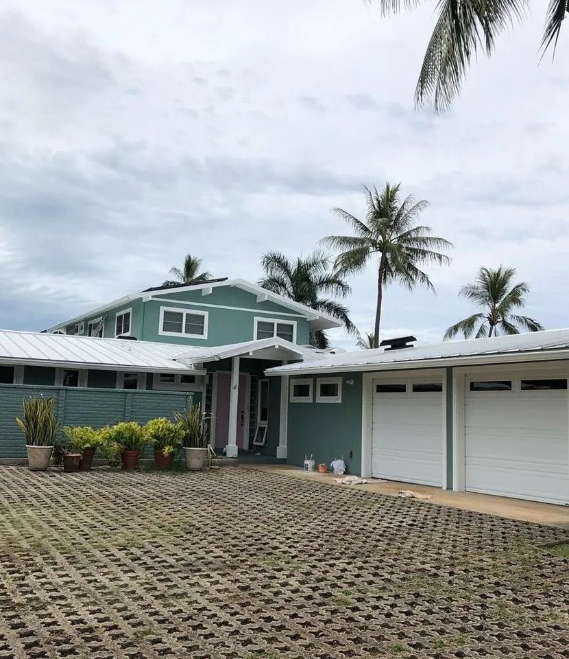 The same home painted teal with white trim and garage doors