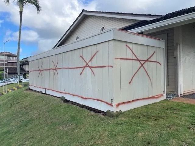 Townhome fence wall with damaged boards marked with red crosses for repair