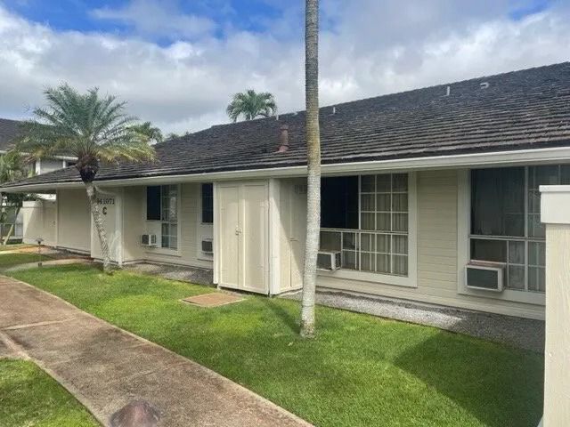 The same townhome row repaired and painted cream, the lawn cleared