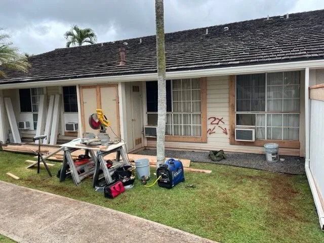 Row of single-story townhomes marked for repair, with saws and tools on the lawn