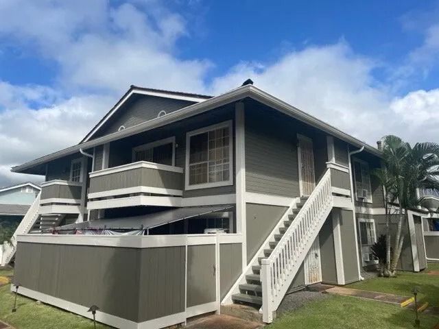 The same building painted gray with white trim, stair rails and fence cap