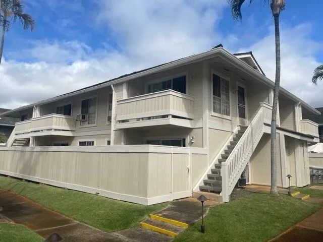 Two-story townhome building in cream with a white outside staircase and fence