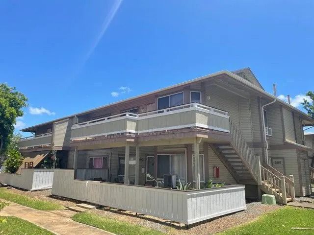 Two-story condo building in faded khaki with white railings and a lawn