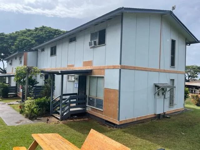 Two-story walk-up in pale blue with new siding panels still unpainted