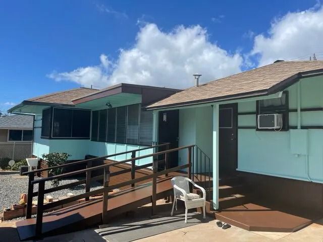 Aqua single-story home with dark trim and a wooden access ramp