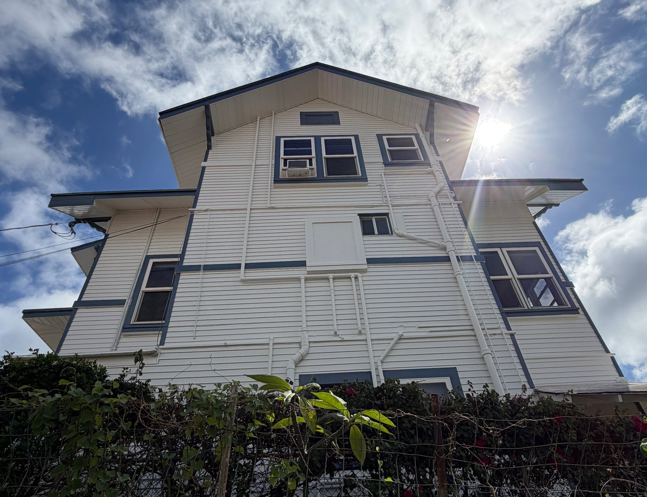 Tall white gable end with blue trim and white downspouts, seen from below