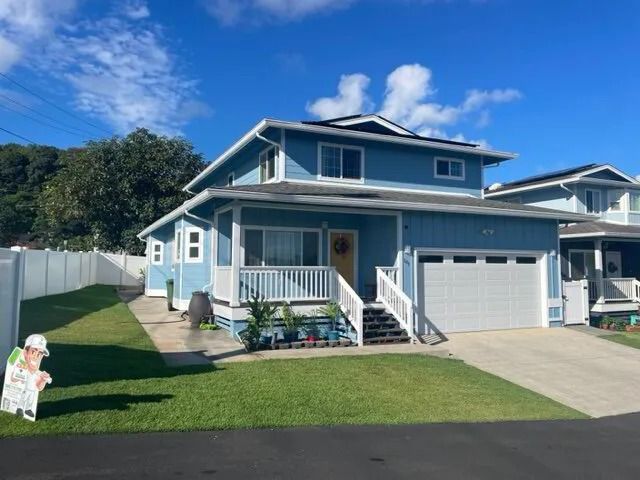 Blue two-story home with white porch railings, a white garage door and a lawn
