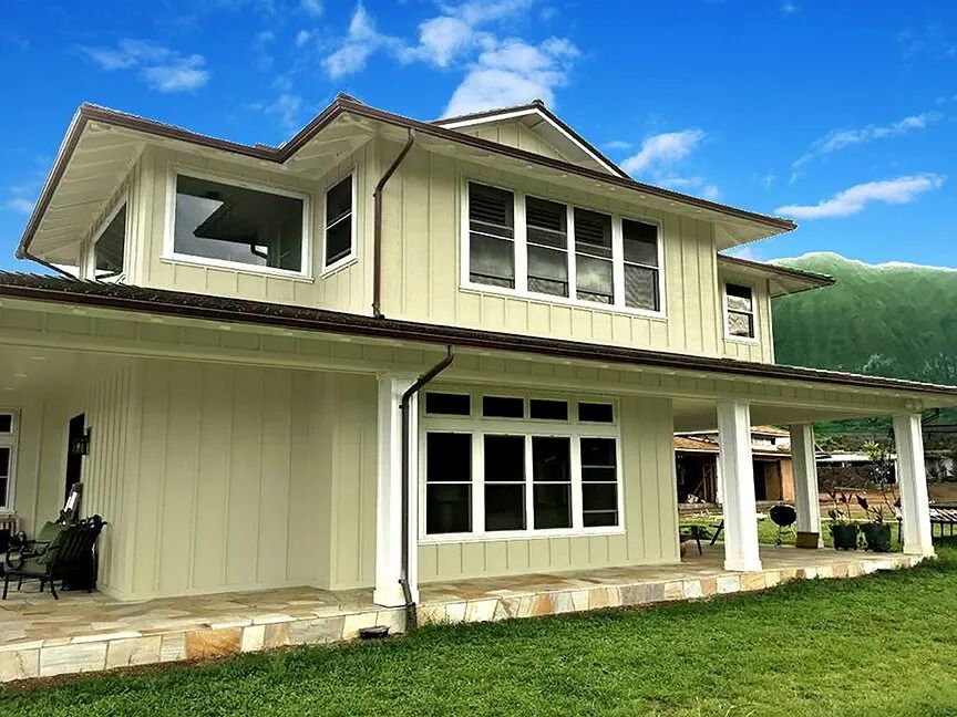 Cream two-story home with white columns around a wraparound stone lanai