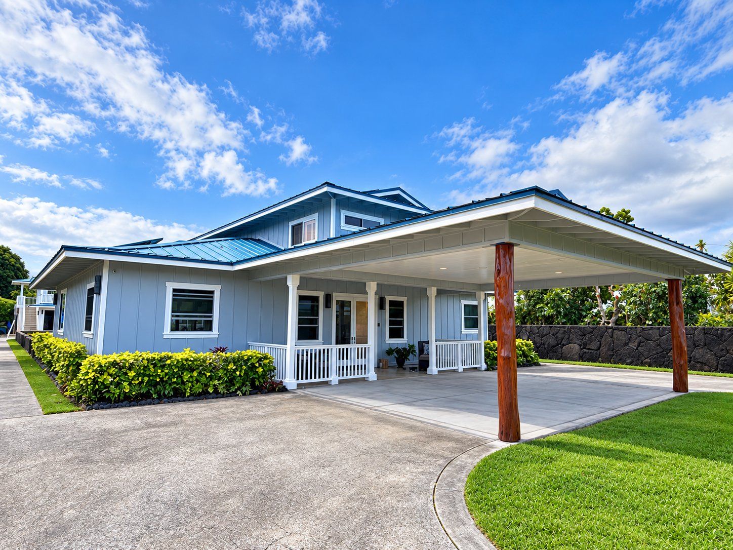 Two-story Kailua home in blue-gray board-and-batten siding with white trim and a carport on natural ʻōhiʻa posts