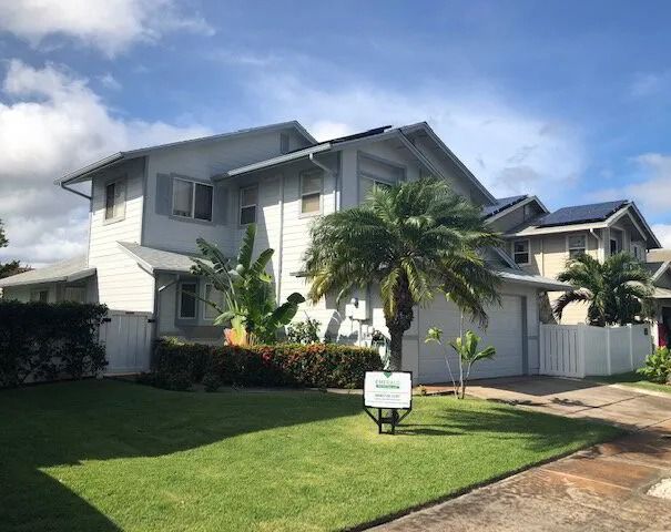 White two-story home with gray trim and a wide front porch, behind a lawn and a palm