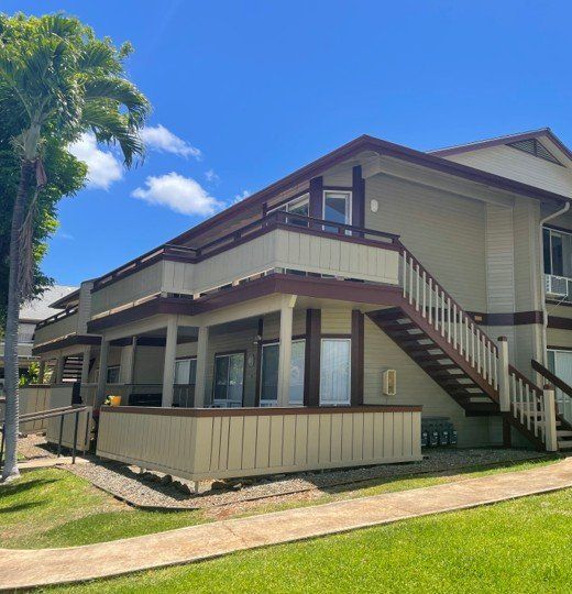 Two-story condo building in khaki siding with maroon trim and an outside staircase